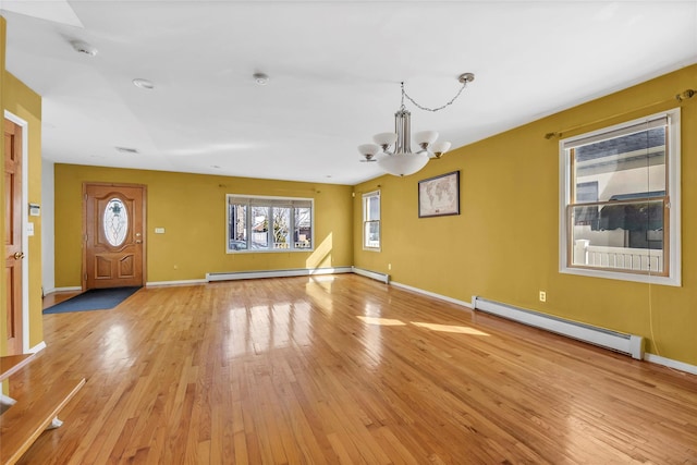 unfurnished living room with light wood-type flooring, a baseboard radiator, a notable chandelier, and baseboards