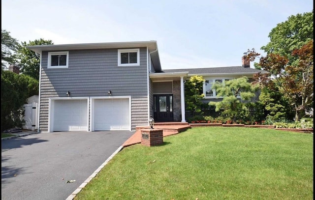 tri-level home with aphalt driveway, a garage, and a front lawn