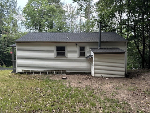 rear view of property with roof with shingles and a lawn