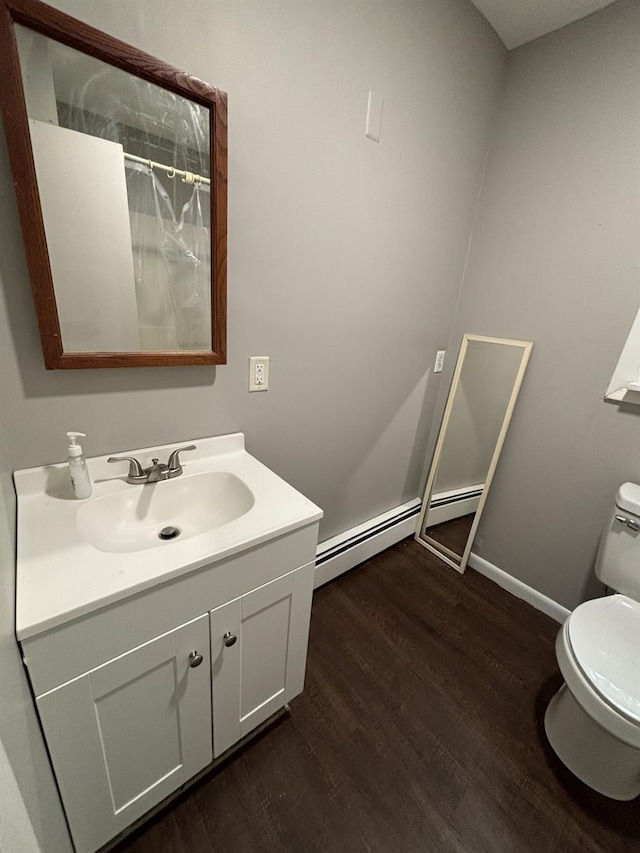 bathroom with toilet, wood finished floors, vanity, baseboards, and baseboard heating