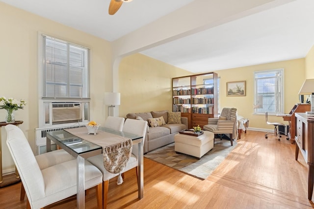 dining area with ceiling fan, cooling unit, baseboards, light wood-style floors, and radiator heating unit