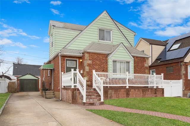 view of front of home featuring a storage shed, roof with shingles, fence, an outdoor structure, and brick siding