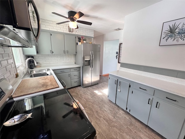 kitchen with tasteful backsplash, stainless steel fridge with ice dispenser, light countertops, gray cabinets, and a sink