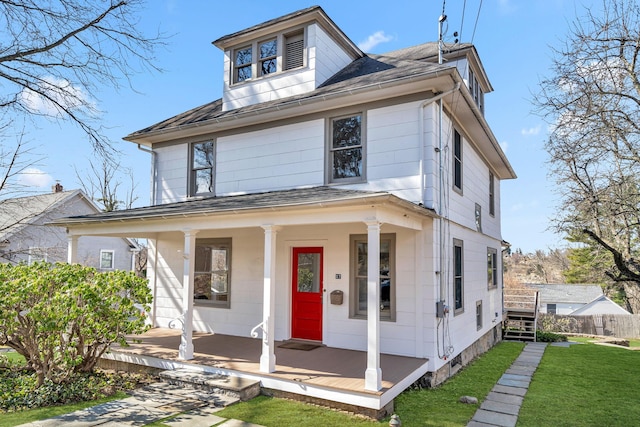 traditional style home featuring a front yard, covered porch, and roof with shingles