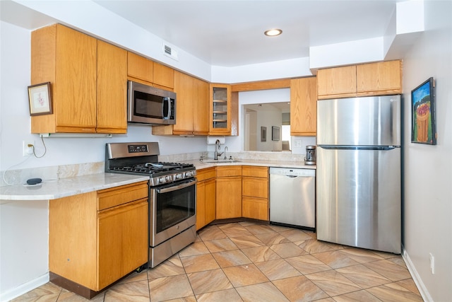 kitchen with visible vents, glass insert cabinets, appliances with stainless steel finishes, light countertops, and a sink