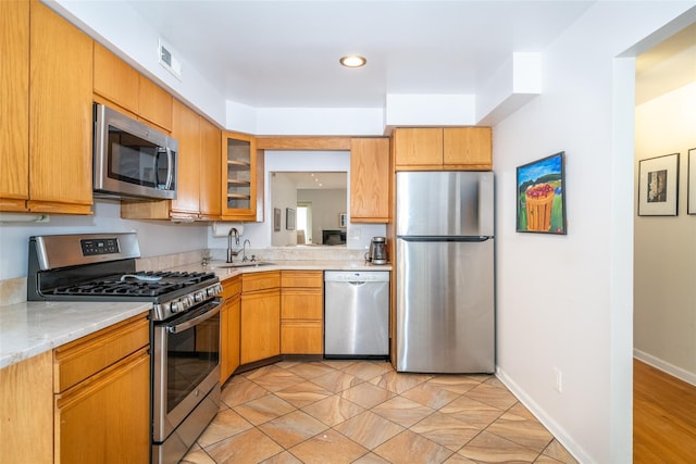 kitchen with a sink, visible vents, baseboards, appliances with stainless steel finishes, and glass insert cabinets