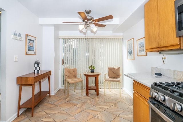 kitchen featuring light countertops, appliances with stainless steel finishes, a ceiling fan, and baseboards