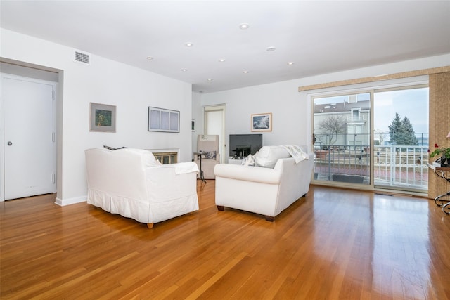 living room with light wood finished floors, visible vents, and recessed lighting