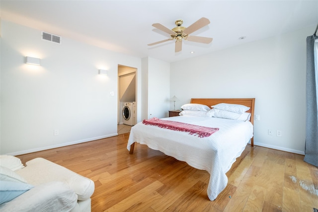 bedroom with light wood-style floors, visible vents, independent washer and dryer, and baseboards