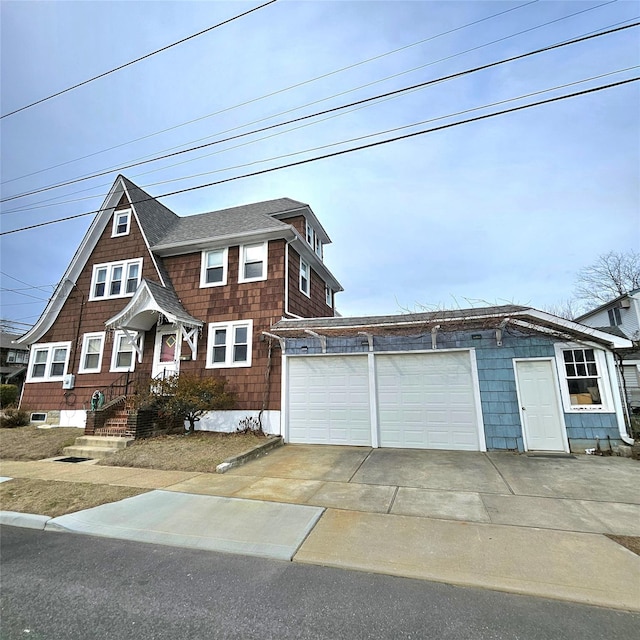 view of front of house with an attached garage, a shingled roof, and concrete driveway