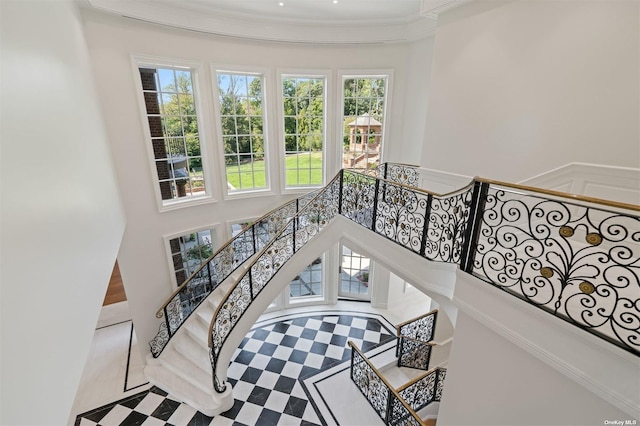 stairs with a towering ceiling and crown molding