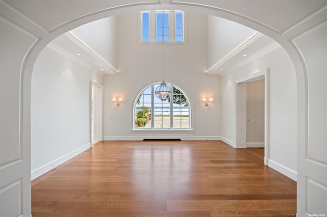 interior space with a chandelier, a high ceiling, baseboards, and wood finished floors