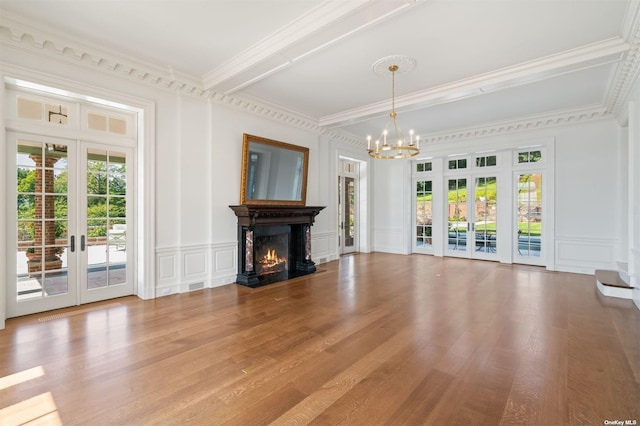 unfurnished living room with french doors, a decorative wall, a lit fireplace, and wood finished floors