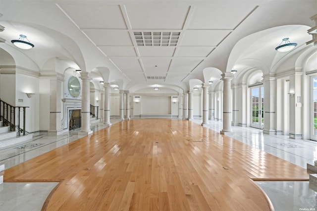 interior space featuring wood-type flooring, a fireplace with raised hearth, and ornate columns