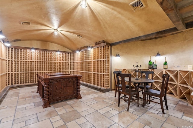 wine cellar featuring stone tile floors, visible vents, and vaulted ceiling