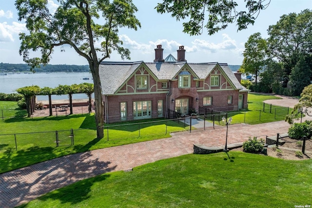 exterior space with a fenced front yard, french doors, brick siding, a chimney, and a front lawn