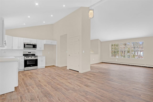 kitchen featuring a baseboard heating unit, stainless steel appliances, white cabinets, open floor plan, and light countertops