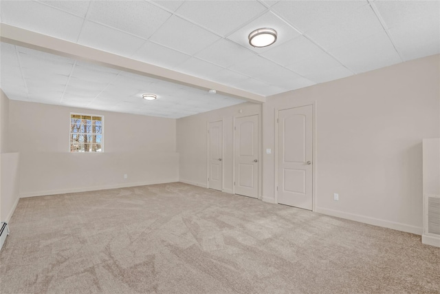 below grade area with light carpet, baseboards, and a paneled ceiling