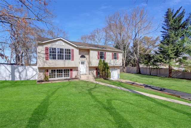 split foyer home featuring fence, entry steps, concrete driveway, a front lawn, and a garage