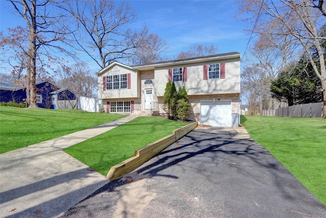 raised ranch featuring a front yard, fence, a garage, and driveway