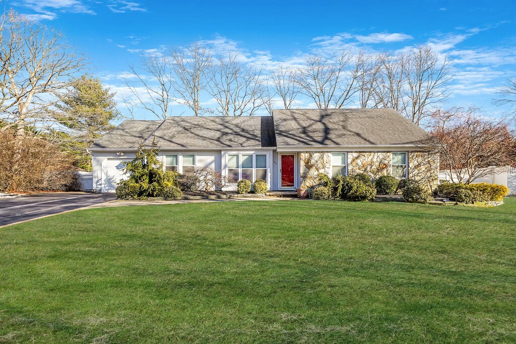 ranch-style home featuring a garage and a front lawn