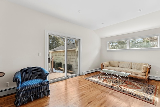 living area with vaulted ceiling, a baseboard radiator, and wood finished floors