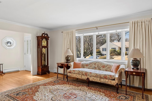 sitting room with baseboards, a baseboard heating unit, crown molding, and wood finished floors