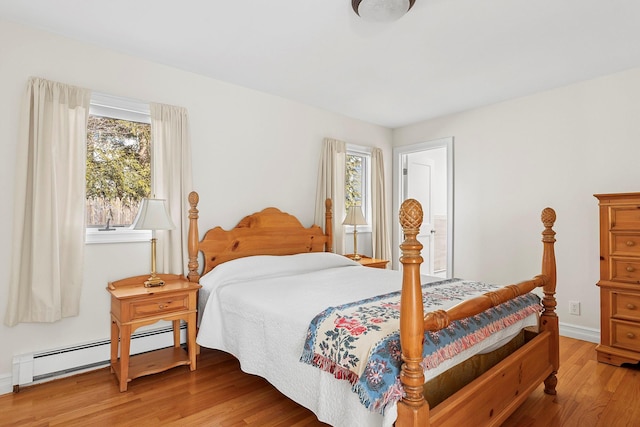 bedroom featuring a baseboard heating unit, baseboards, and wood finished floors