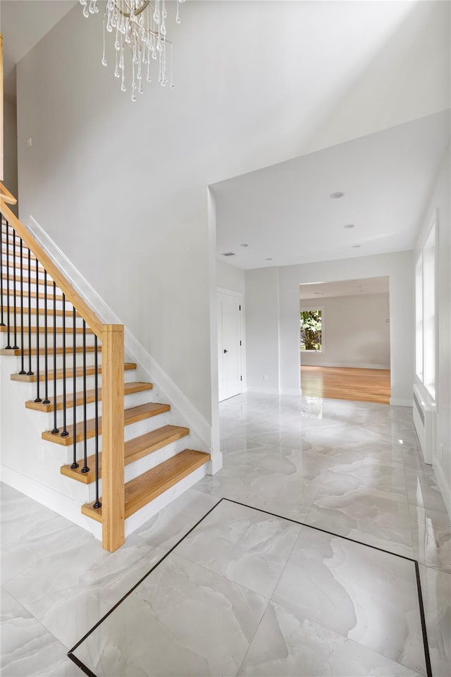 staircase featuring a chandelier, marble finish floor, and baseboards