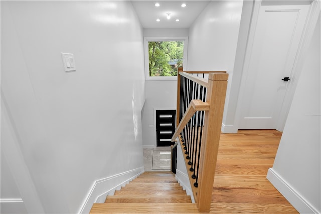 stairway featuring recessed lighting, wood finished floors, and baseboards