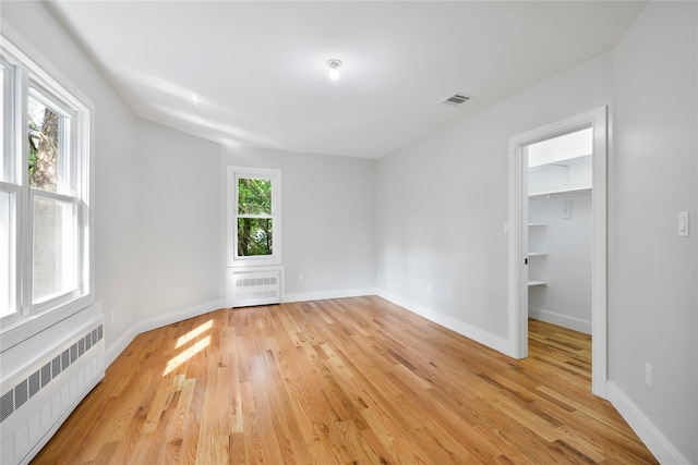 unfurnished room featuring light wood-type flooring, baseboards, and radiator heating unit