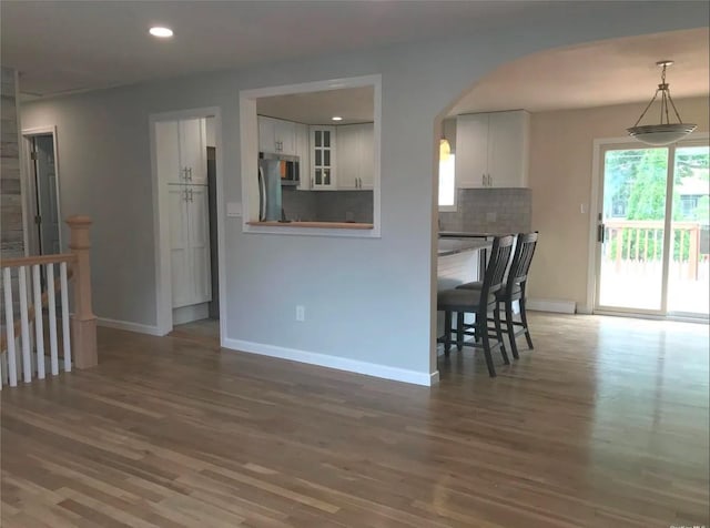 interior space featuring arched walkways, wood finished floors, baseboards, and recessed lighting