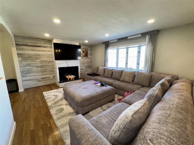 living area featuring a fireplace, wood finished floors, baseboards, and recessed lighting