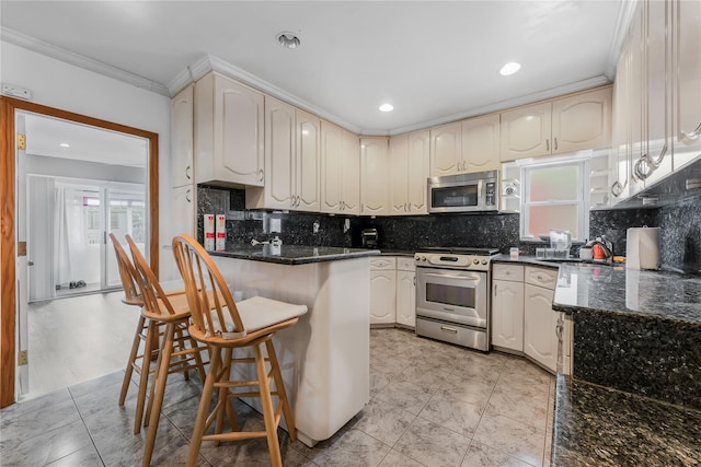 kitchen with a breakfast bar, stainless steel appliances, backsplash, ornamental molding, and dark stone counters