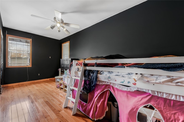 bedroom with a ceiling fan, baseboards, and wood finished floors