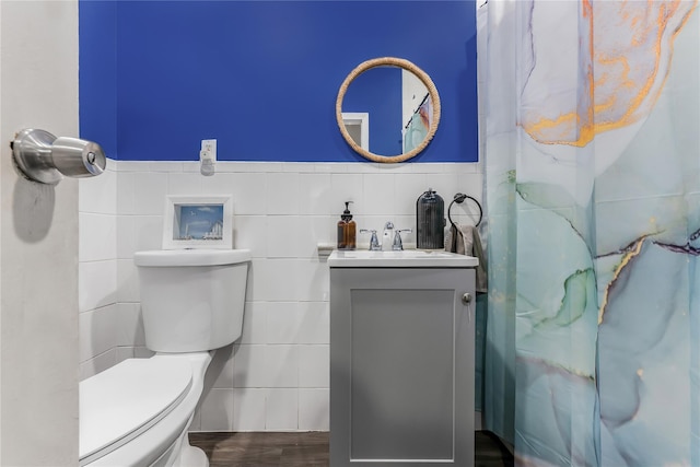 full bath with wainscoting, toilet, a shower with curtain, vanity, and tile walls