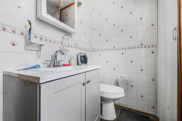 half bath with toilet, vanity, and tile walls