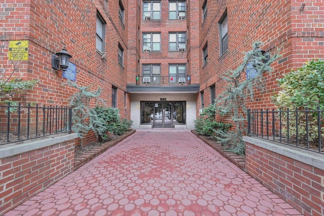 property entrance with french doors, brick siding, and fence