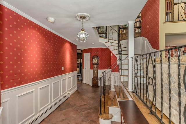 hallway with wallpapered walls, a wainscoted wall, a baseboard radiator, ornamental molding, and stairs