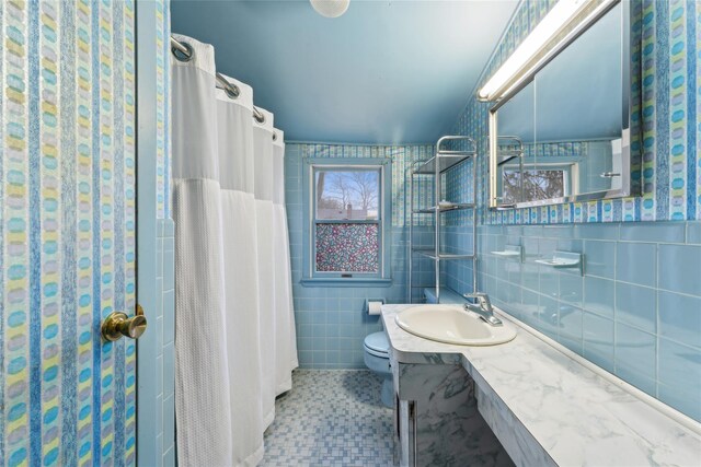 bathroom with toilet, curtained shower, vanity, and tile walls