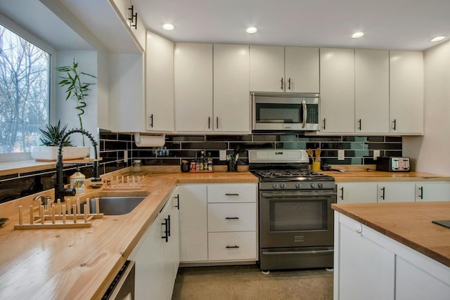 kitchen featuring decorative backsplash, butcher block countertops, and appliances with stainless steel finishes