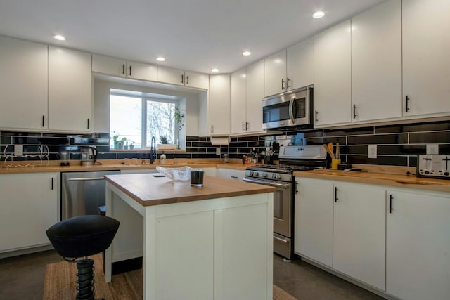 kitchen featuring a sink, stainless steel appliances, tasteful backsplash, and butcher block counters