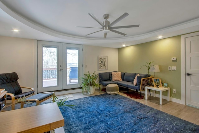 living area with recessed lighting, french doors, a tray ceiling, and wood finished floors