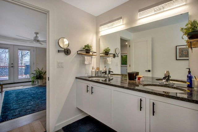 bathroom featuring double vanity, french doors, baseboards, and a sink