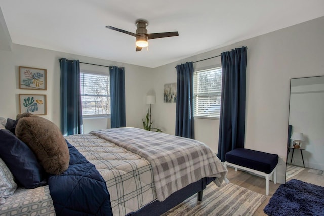 bedroom featuring multiple windows, wood finished floors, and a ceiling fan