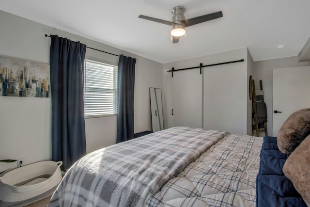 bedroom with ceiling fan and a barn door