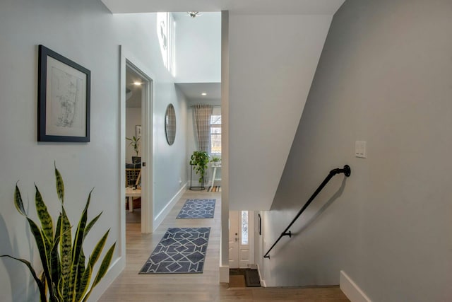 corridor featuring light wood-type flooring and baseboards