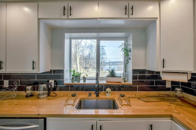 kitchen featuring tasteful backsplash, wooden counters, and a sink