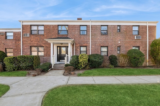 view of front of house featuring a front yard, a chimney, and brick siding