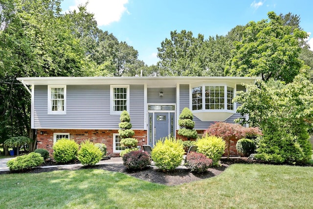 split foyer home featuring brick siding and a front lawn